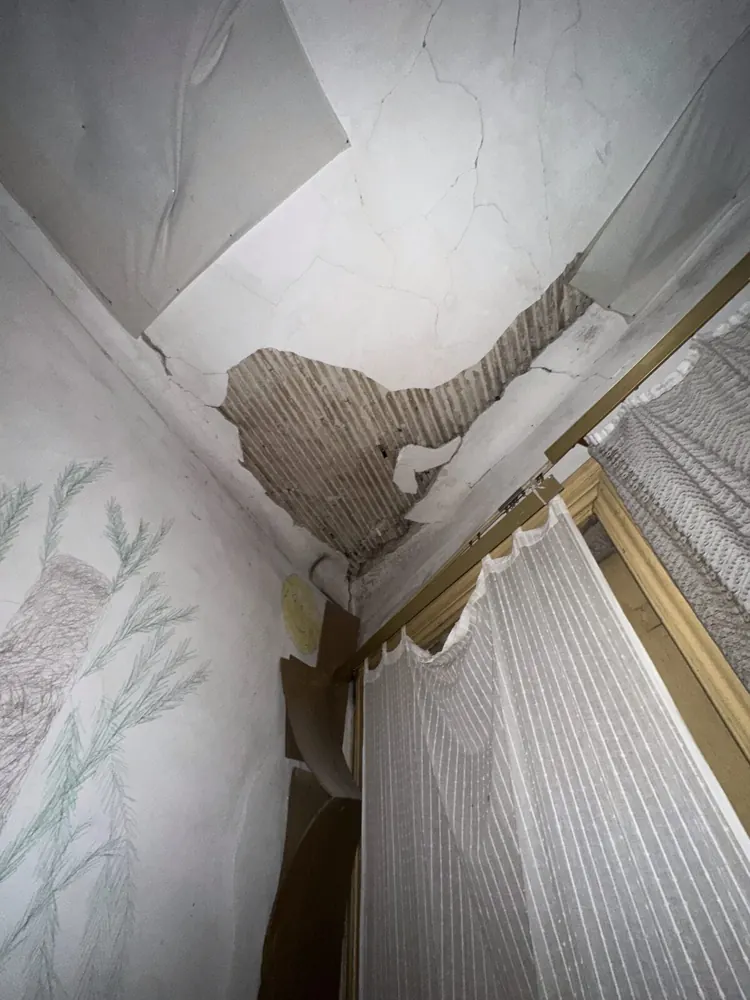 Ceiling plaster cracked and coming away in the corner of a room in an old Porto house