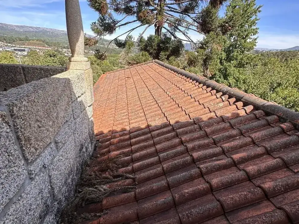 Clay tile roof against a granite parapet with debris in the valley