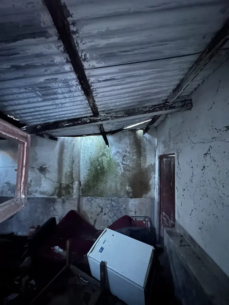 Collapsed roof over the rear annex of an old house, with debris inside