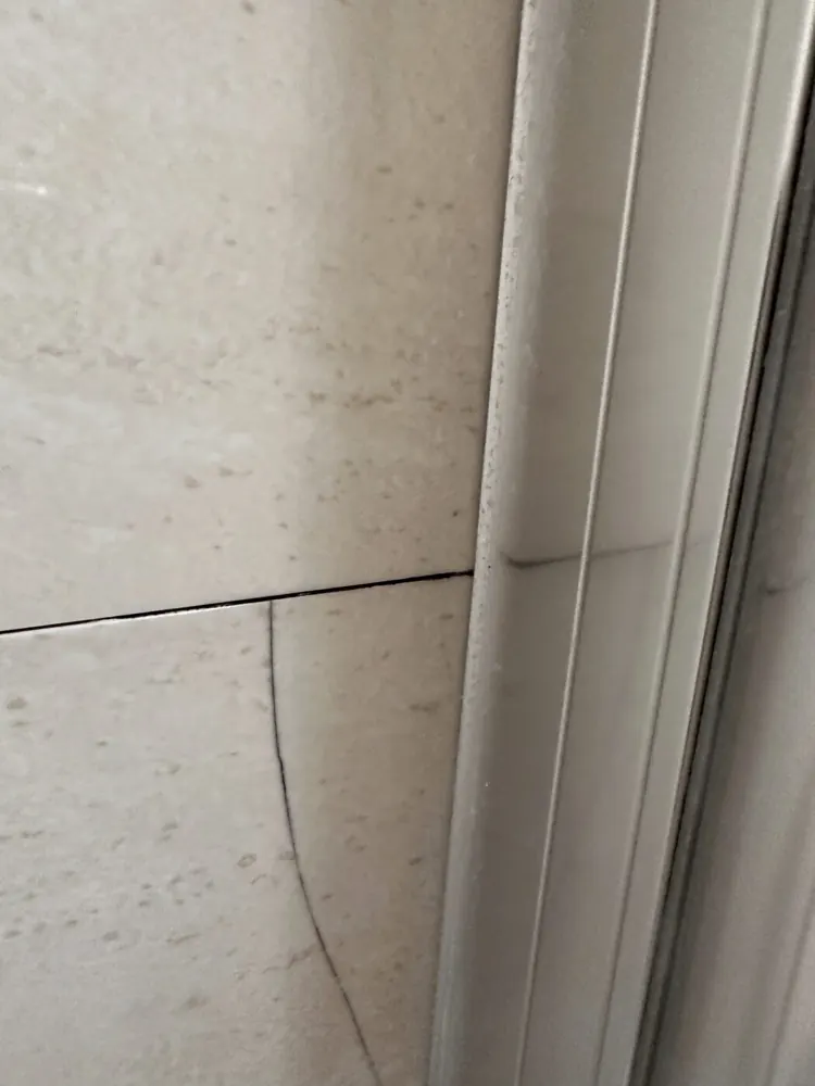 Crack running through a wall tile beside a shower