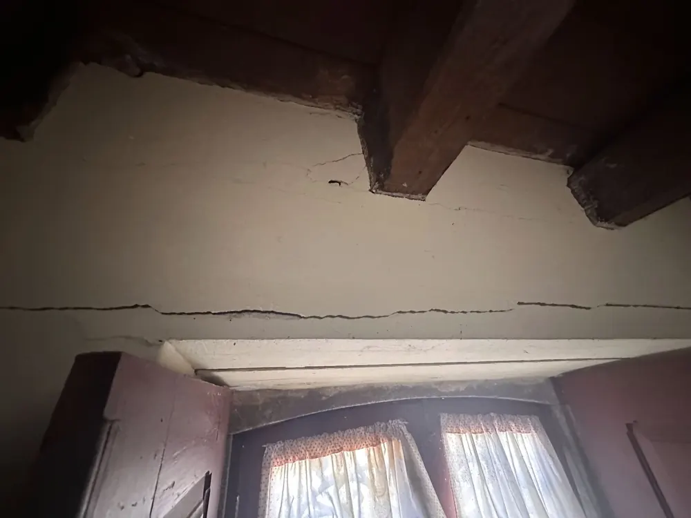 Long crack in the wall below old timber floor beams