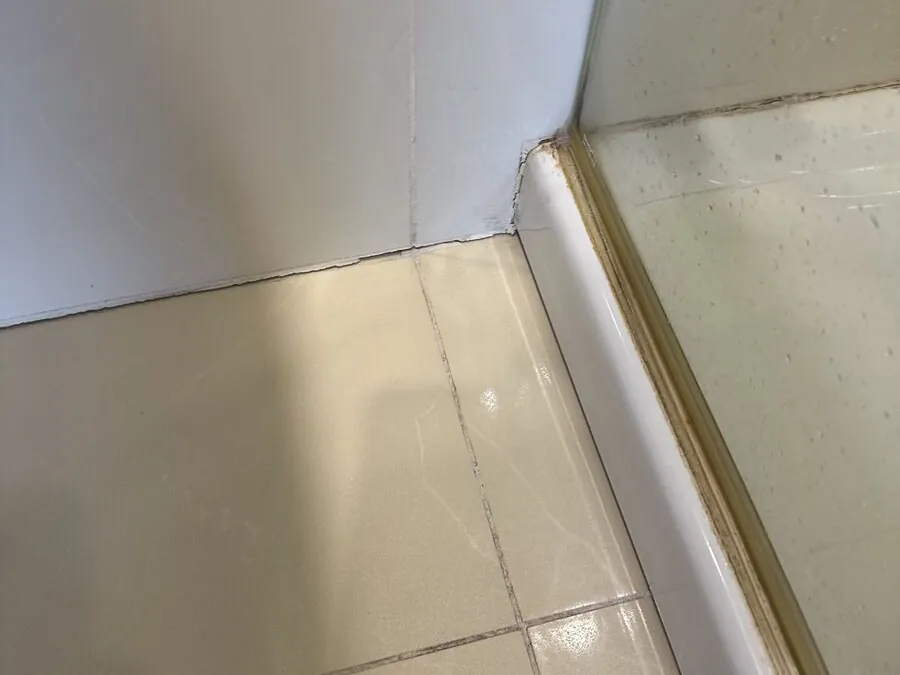 Discoloured silicone along the edge of a shower tray