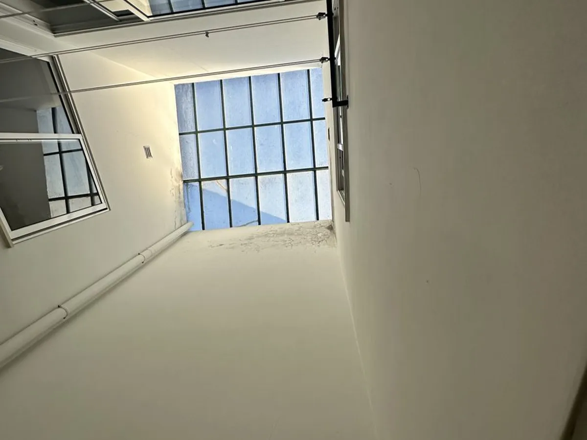 Old steel-framed skylight over an internal light well with staining at the top corner