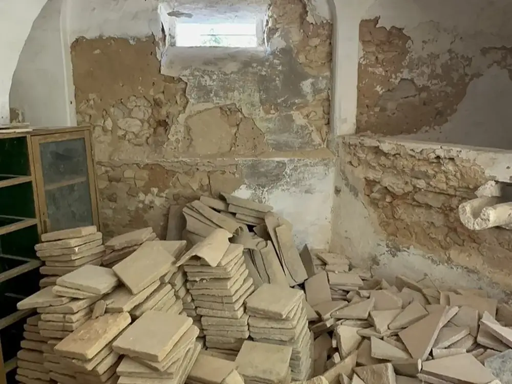 Derelict vaulted room with stripped plaster and stone rubble piled on the floor