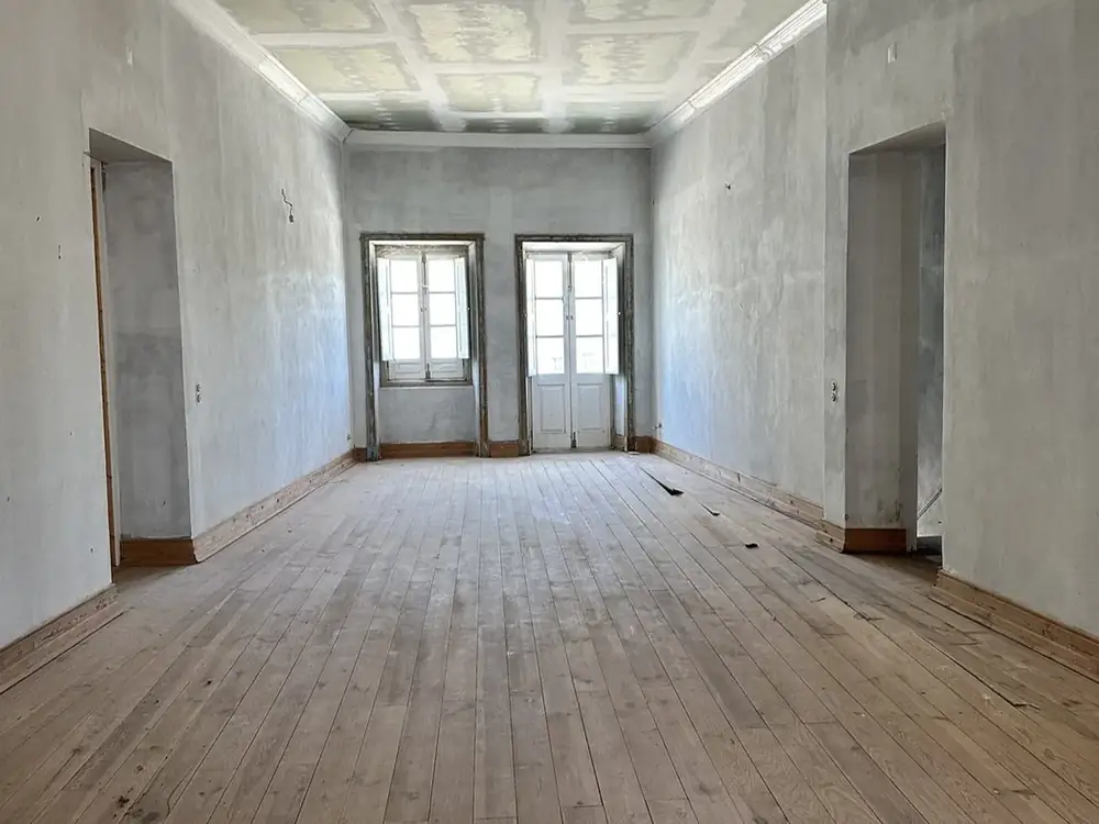 Restored principal room in a manor house with coffered ceiling, tall double doors and wide timber floor
