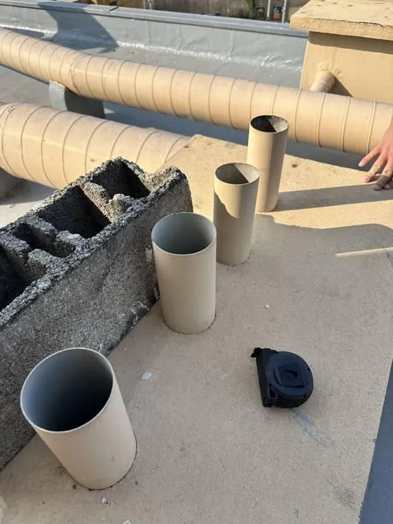 Vent pipes cut off as open stubs beside unsealed hollow concrete block on a roof