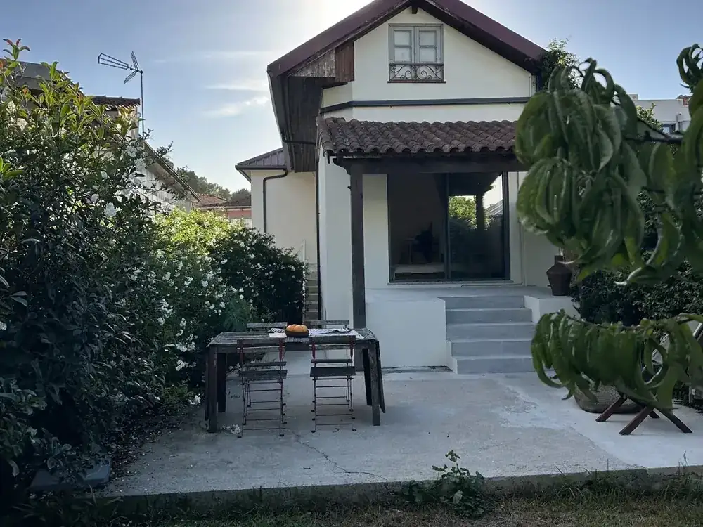 Alçado posterior de uma moradia remodelada com terraço coberto e jardim