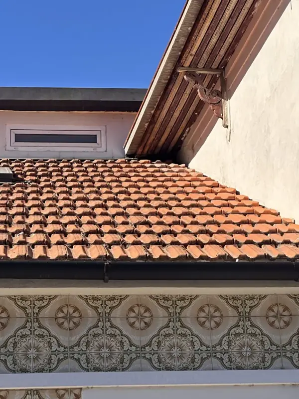Clay tile roof and gutter above an azulejo-tiled facade in Porto