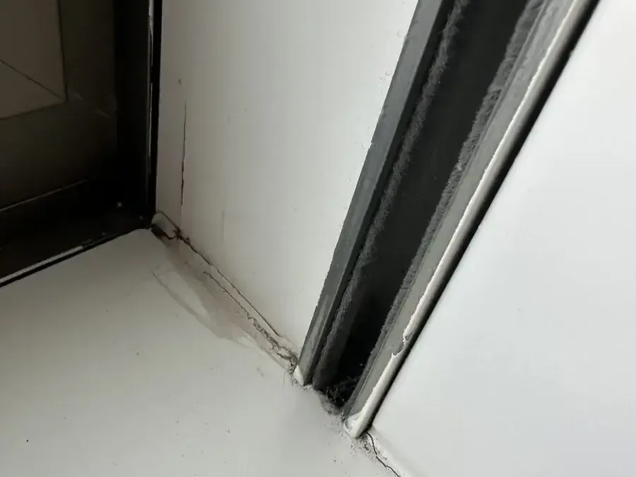Crack along the junction of a window sill and reveal with a water mark above