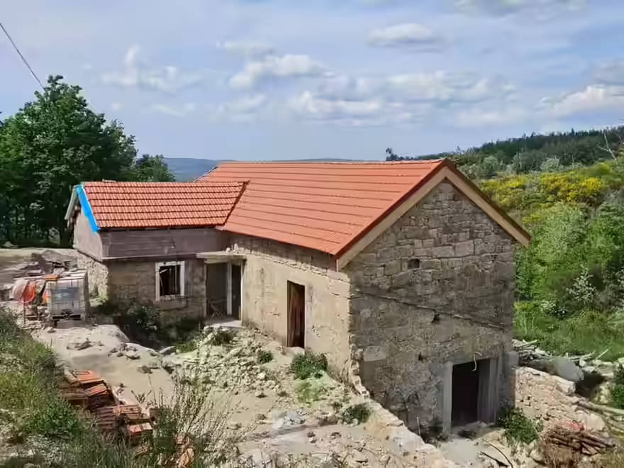 Granite quinta under restoration in rural northern Portugal, new terracotta roof on original stone walls