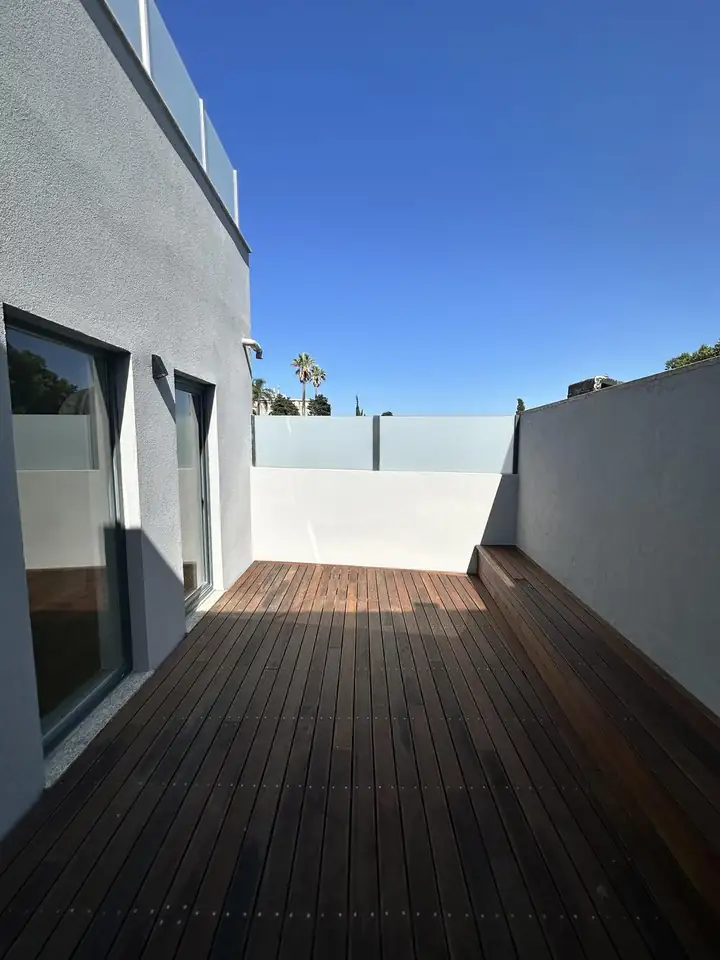 Rooftop terrace with hardwood decking and glass privacy screens on a Porto renovation